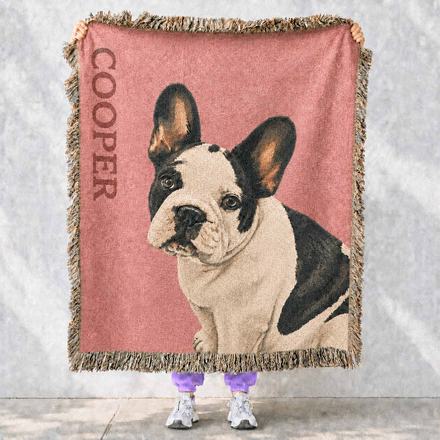Custom pet Blanket with a frenchie dog illustration and 'Cooper' text, held by two people against a light gray background. 